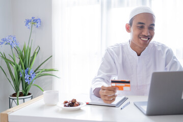 muslim asian man using credit card for online shop payment transaction