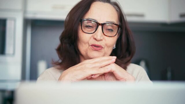 Portrait Of A Senior Mature Older Woman Making A Video Call With Family Or Friends On A Laptop Computer. 60s Woman Video Conference Calling In Virtual Chat.