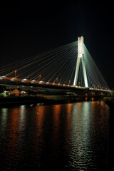 Fototapeta premium 大阪府池田市と兵庫県川西市の県境、夜の猪名川と阪神11号池田線新猪名川大橋・ライトアップされたビッグハープ