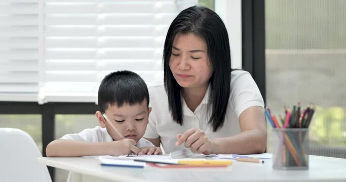 Mother and son doing homework at home, Mother is teaching son to draw pictures, Children homework. Young boy. doing homework on the terrace at home. Happy mood. Back to school concept.