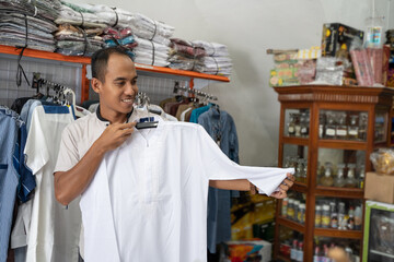 Portrait of a young asian muslim man shopping for clothes at store