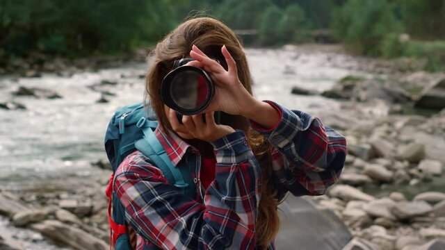 Girl photographing in mountains. Female professional taking photos outdoor