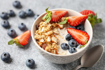 Oatmeal granola with yogurt, berries and nuts in a bowl on the table. Healthy breakfast