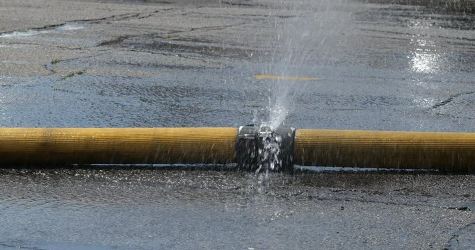Water spraying onto the street from a joint in a firehose