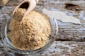 nutritional yeast in flakes, deactivated, not live, B vitamins, wooden background, close-up, top view