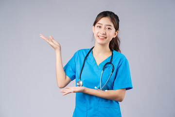 Image of young Asian female doctor wearing blue uniform on grey background