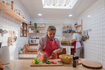 Happy Asian elderly family eating at home. Smiling senior couple enjoy cooking together in the kitchen. Retirement family husband and wife having fun leisure activity lifestyle at home with happiness
