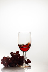 Red wine in glass with red grape.