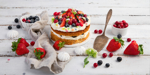 Delicious homemade cake with fresh berries and mascarpone cream on wooden background.