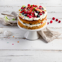Delicious homemade cake with fresh berries and mascarpone cream on wooden background.