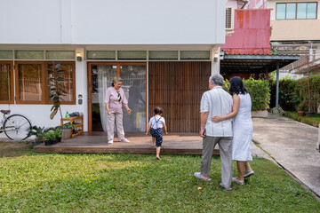 Happy Asian multi-generation family spending time together at home. Parents with cute baby child girl visit grandparents at home. Family relax and having fun weekend vacation together with happiness