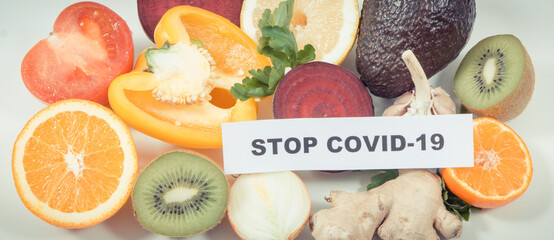 Inscription stop covid-19 and fresh fruits with vegetables. Source natural vitamins and minerals. Beneficial eating in times of Covid-19