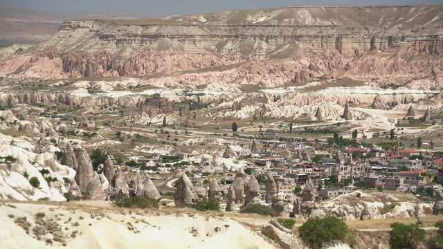 Goreme and traditional cave houses architecture on the edge of fairy chimneys in Cappadocia.Limestone hoodoos and sedimentary fairy chimney rocks in an arid basin valley.Turkey urgup city town view 4K
