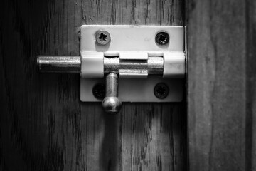 A small white metal latch on a wooden door.
