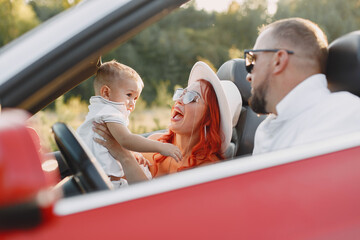 Family in a cabriolet convertible car at the sunset