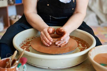 Hands of a master working with clay on a potter's wheel.