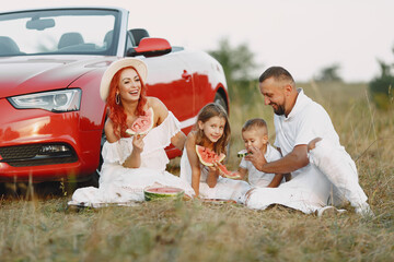 Family sitting by the red cabriolet