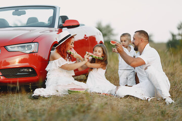Family sitting by the red cabriolet