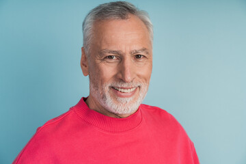 Obraz premium Close-up view, senior man smiling on blue background. Attractive man in a bright pullover.