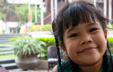 closeup portrait of adorable little Asian girl smiling happily wearing green dress while enjoying traveling with family during holiday