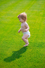 Warm spring time in the park. Baby in beautiful spring green field. First step.