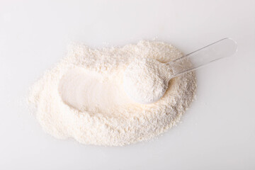 Heap of white protein powder with measuring spoon
