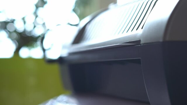 Close-up of a laminated white sheet of paper coming out of the laminator
