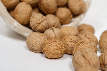 ripe walnuts pour out of a wicker basket onto a white table.
