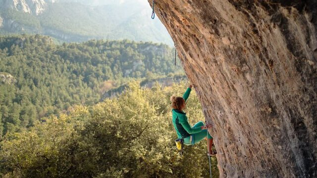 strong and powerful woman rock climber climbs hard tough rock route on overhanging cliff on beautiful natural background in Turkey. mountain and rock climbing
