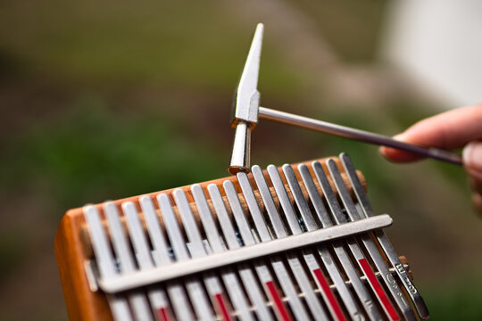 Folklore musical instruments concept. A woman tunes a musical instrument Kalimba with a hammer.