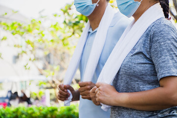 Senior couple Asian men and women are spraying each other with alcohol. People put on face masks and exercise clothes before morning exercise.