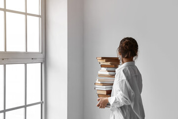 Woman with stack of books on light background