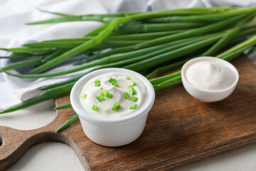 Fototapeta na wymiar Bowls of tasty sour cream and green onion on table