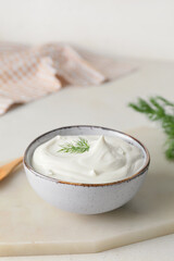 Obraz na płótnie Canvas Bowl of tasty sour cream on light background