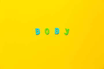 The word Boby made of colored plastic letters with magnets on a yellow background with copy space,...