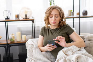 Pregnant woman lying on the couch holding smartphone in hand