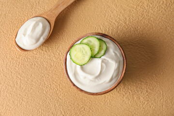 Bowl and spoon with tasty sour cream on color background