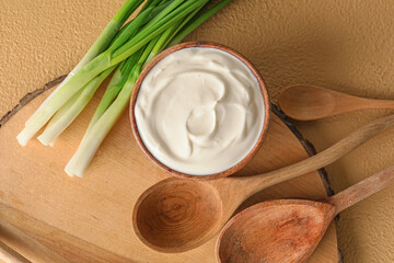 Fototapeta na wymiar Bowl with tasty sour cream and green onion on light wooden background
