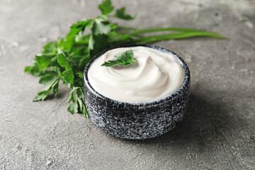 Bowl of tasty sour cream and herbs on grunge background
