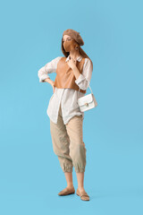 Fashionable young woman wearing mask on color background