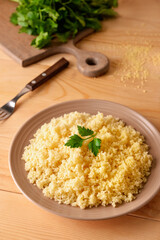 Plate with tasty couscous on wooden background