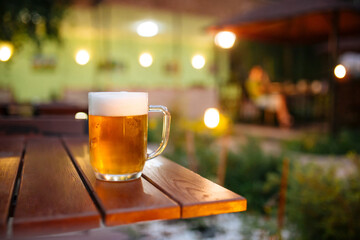 Glass mug of fresh cold beer on the table in summer terrace
