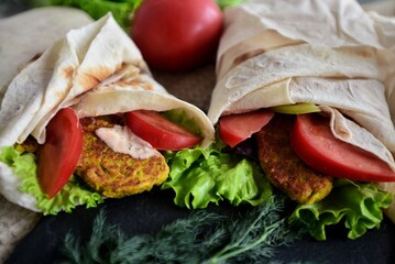 vegetables wrapped in pita bread, vegetable roll, dill, lettuce and tomato lie side by side
