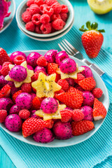 Fresh dragon fruit salad with strawberries, rspberries and start fruit (carambola)