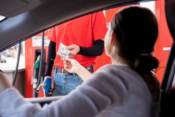Attendant service worker receiving money from hand of customer at gas station. Customer giving...