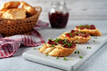 Sandwich with homemade mayonnaise, sun-dried tomatoes and micro greens, served on a board on a gray background