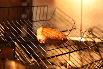 Grilling basket with tuna in oven, closeup