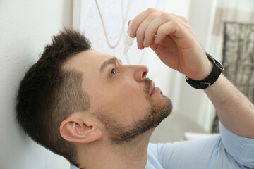 Obraz premium Man using drops for eyes at home