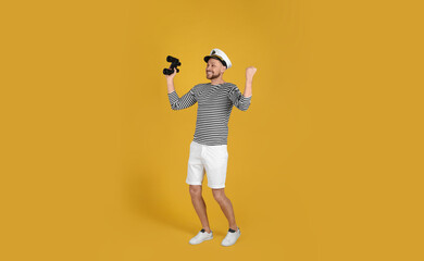 Fototapeta na wymiar Happy sailor with binoculars on yellow background