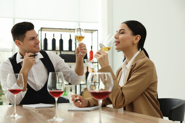 Sommeliers tasting different sorts of wine at table indoors